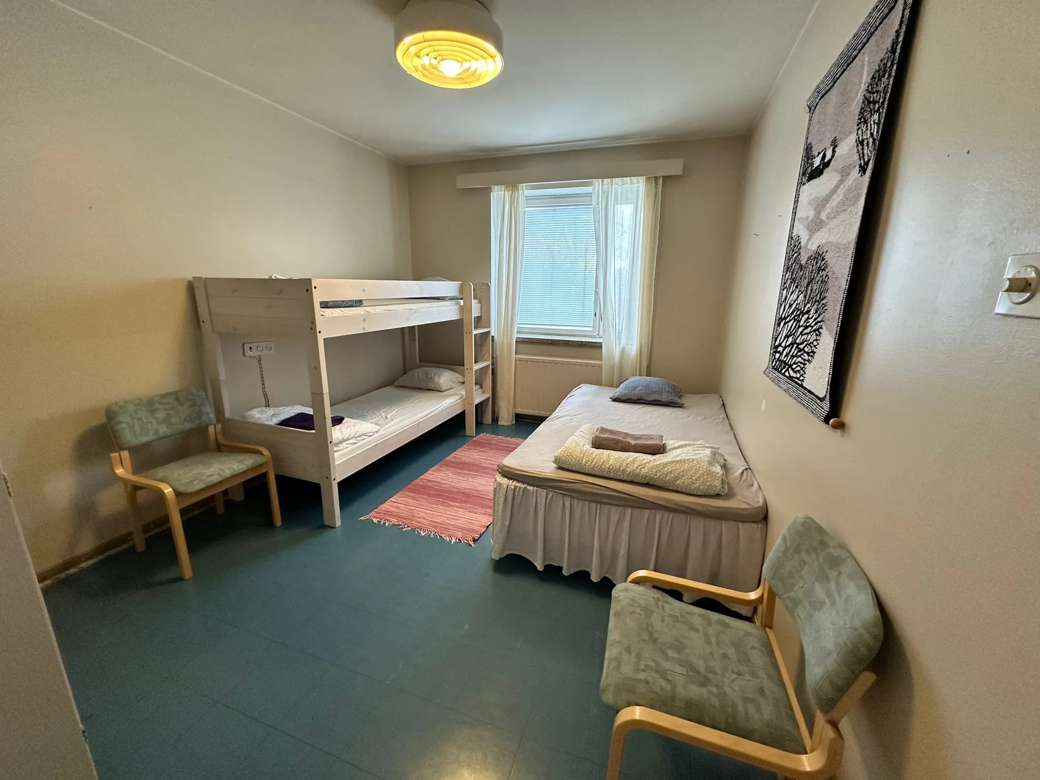 Kolmen hengen huone yhdellä erillisellä vuoteella ja kahdella kerrossängyllä